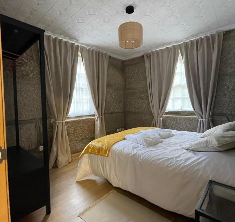 a bedroom with a bed and two windows at Apartamentos A'Dao in Nelas
