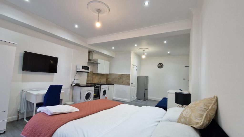 een slaapkamer met een bed, een bureau en een televisie bij Spacious 3-Bedroom Apartment - London in Wanstead
