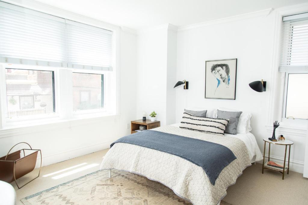 a white bedroom with a bed and two windows at Sleepover No 107 in Philadelphia