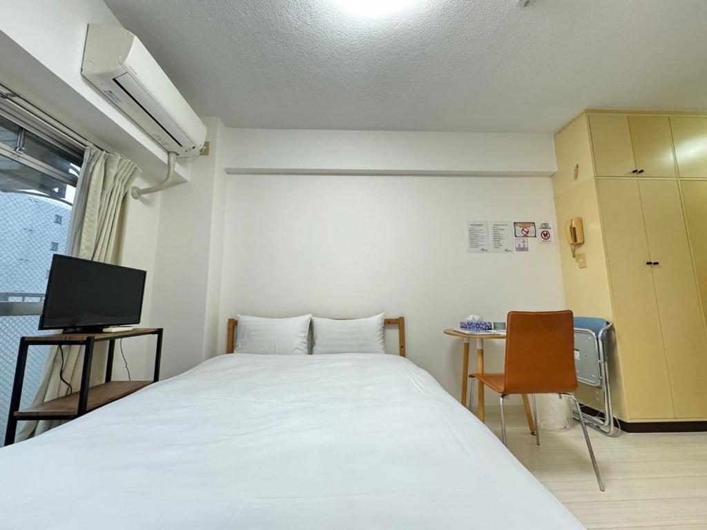 a room with a bed and a desk and a tv at A&C STAY Shin-Osaka Higashikuchi 83 in Osaka