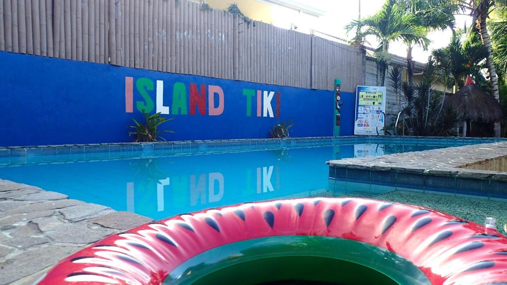 a swimming pool with a red hose in front of a wall at Island Tiki Paradise Resort in Panglao Island
