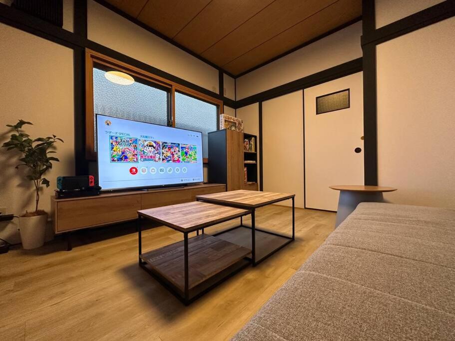 a living room with a flat screen tv and a couch at TasoneUrbanStayOsaka 梅田中津2 in Osaka