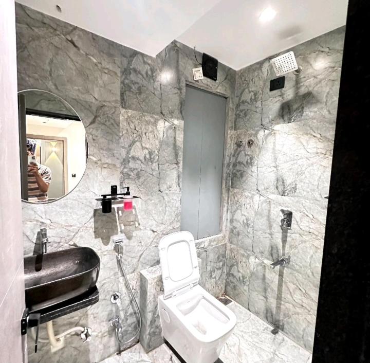 uma casa de banho com um WC, um lavatório e um espelho. em V Love Hotel em Surate