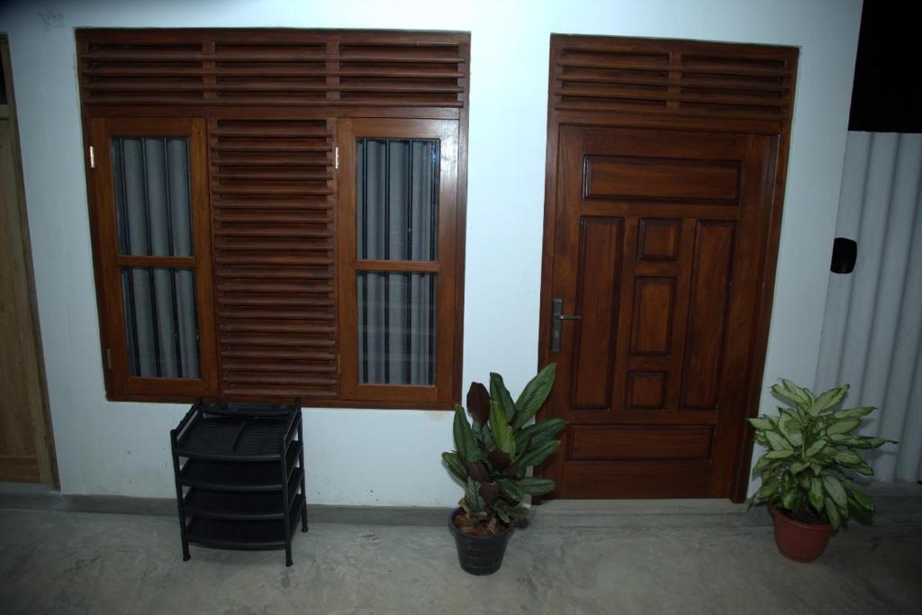 a room with two wooden doors and two potted plants at Happy house mirissa in Kamburugamuwa