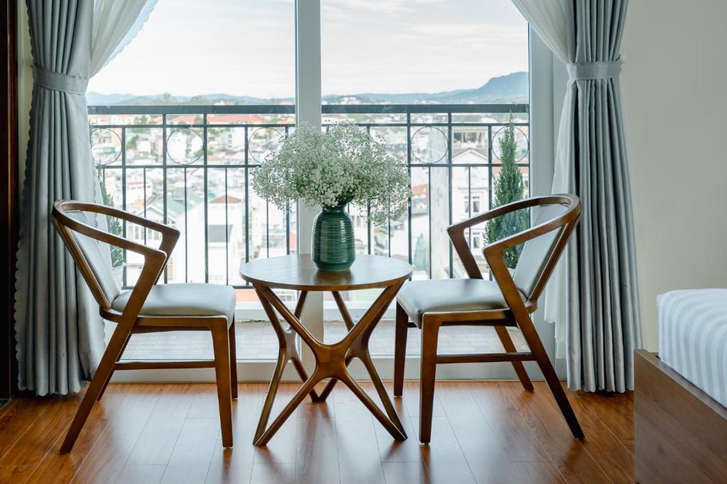 a table with two chairs and a vase with flowers at Bombo DaLat Hotel in Da Lat
