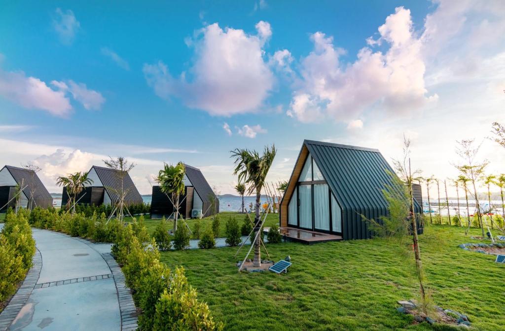 a house with a green roof and a grass yard at Summer Bay Beach Club & Cabins in Sihanoukville