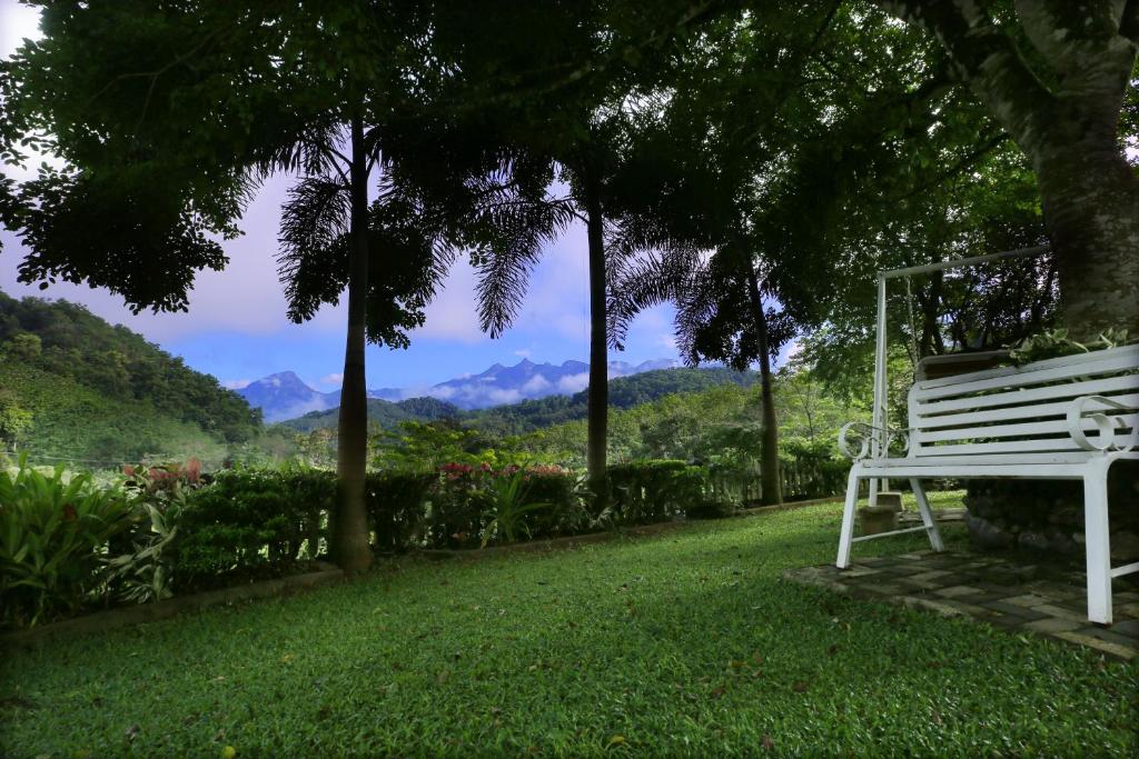 a white bench sitting in the grass with a view at Estate Bungalow in Ratnapura