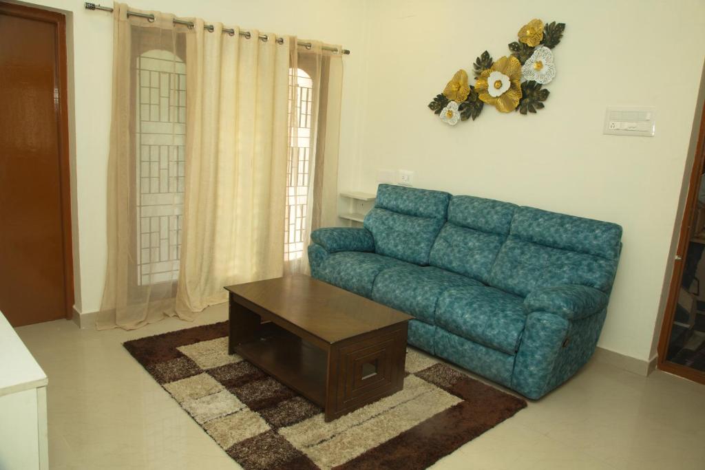 a living room with a blue couch and a coffee table at IZI APOLLO STAY in Chennai