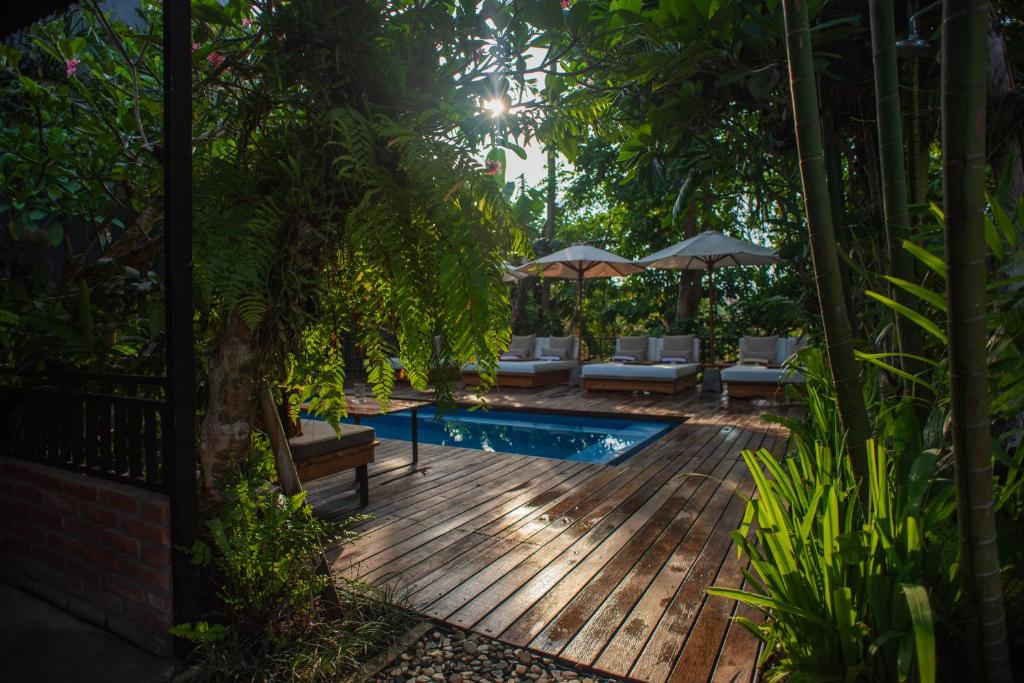 um quintal com um deque de madeira e uma piscina em Pangkung Sari Bed and Breakfast em Canggu