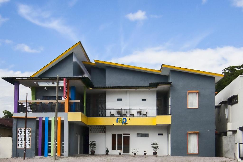 un edificio de color azul y amarillo en RAP Hotel Balige en Balige