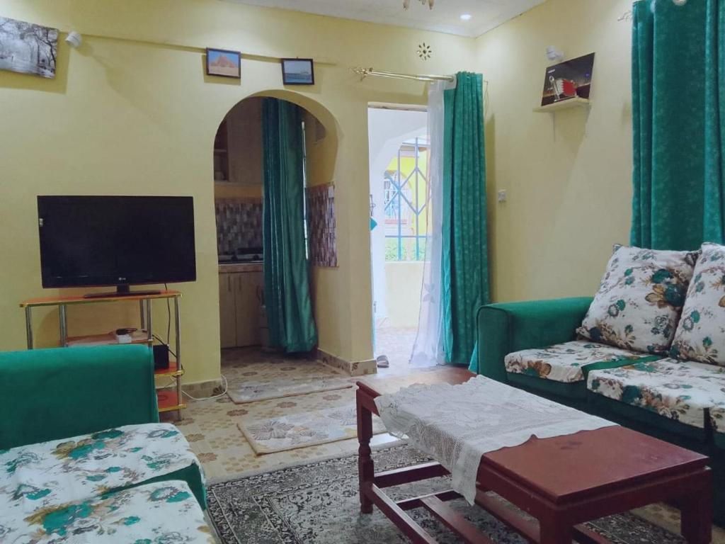 ein Wohnzimmer mit einem Sofa und einem TV in der Unterkunft BONNY KINGs FARMSTAY in Kiambu