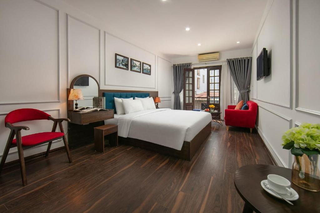 a hotel room with a bed and a red chair at Silk Hanoi Moment Hotel & Spa in Hanoi