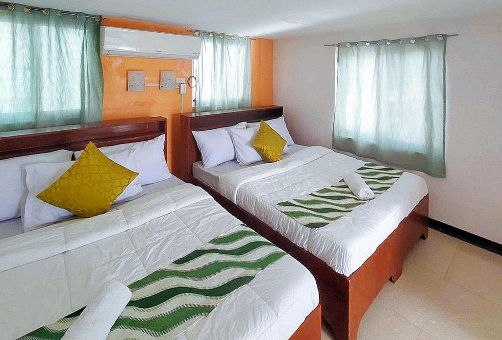 2 Betten in einem kleinen Zimmer mit Fenstern in der Unterkunft RedDoorz @ Recson Hostel Coron Palawan in Coron