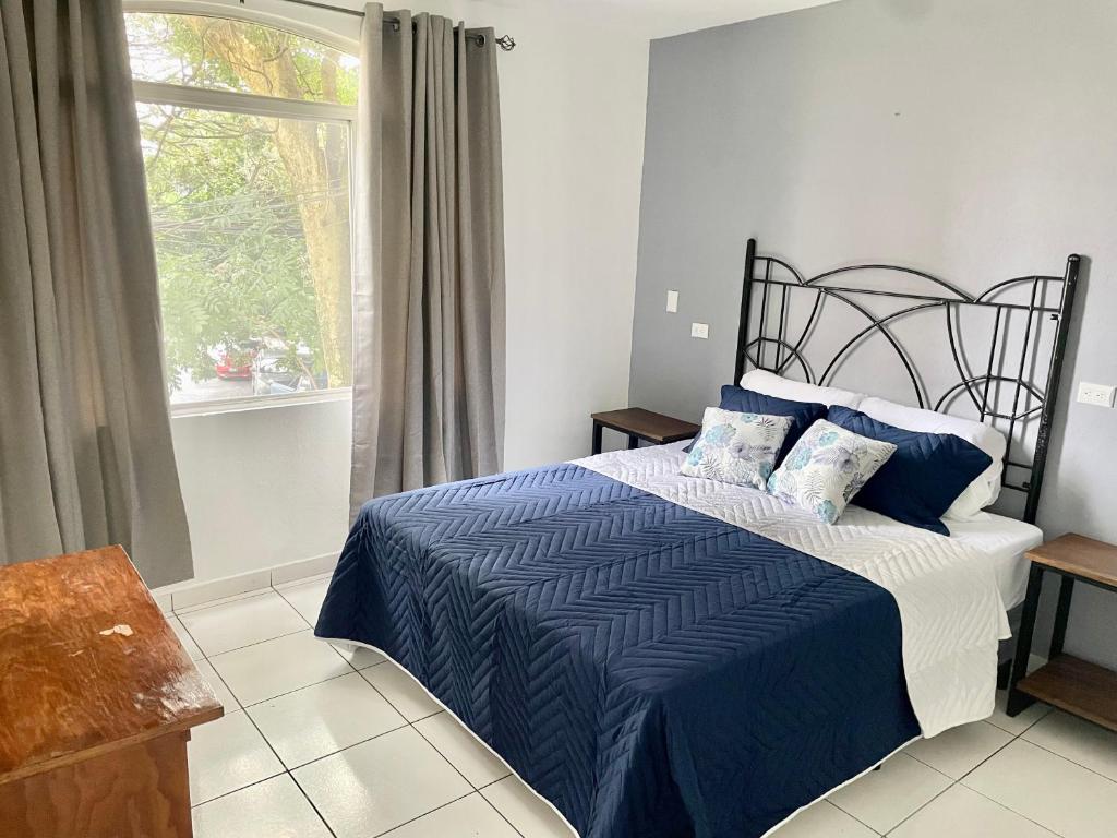 a bedroom with a blue and white bed with a window at Exclusivo apartamento in San Salvador