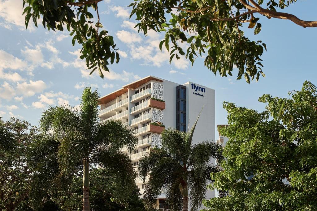 a hotel building with palm trees in the foreground at Crystalbrook Flynn in Cairns