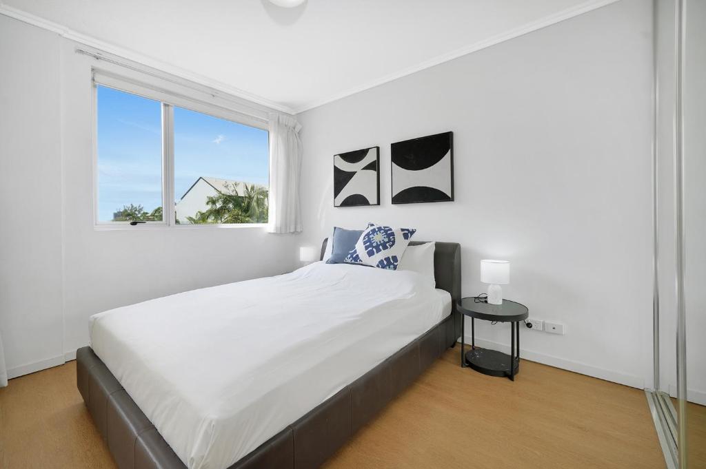 a white bedroom with a large bed and a window at Trilogy Residences Brisbane in Brisbane