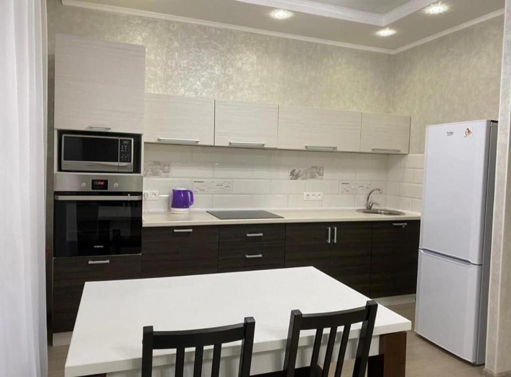 una cocina con electrodomésticos blancos y una mesa y sillas blancas. en City Centre Vip 220, en Tiflis