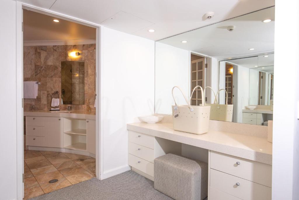 baño con armarios blancos y espejo grande en 71 Hastings Street - Beachfront, en Noosa Heads
