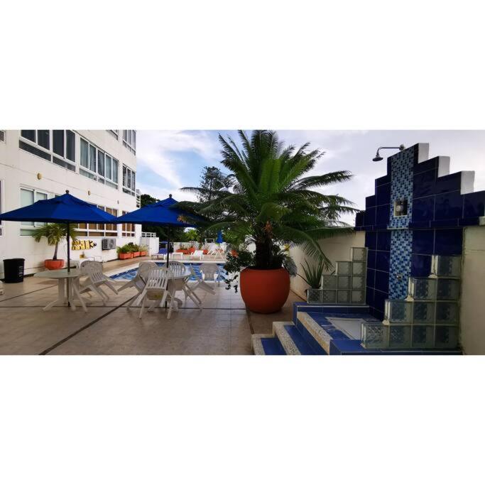 een patio met een palmboom en tafels en parasols bij ocean apartment 310 in San Andrés