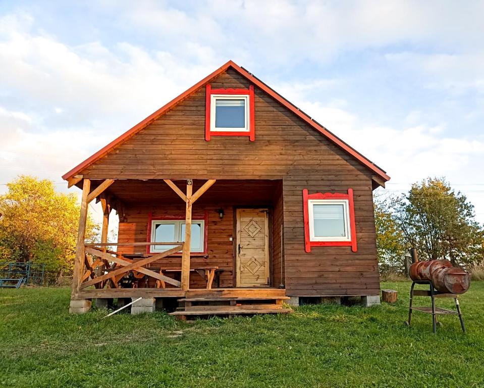 a small log cabin with red windows on a field at Nr3 - W POLU DOBREJ ENERGII 