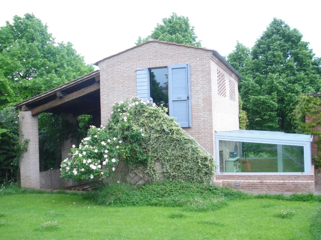 una casa de ladrillo con una ventana y un arbusto de flores en La Vigna Apartment, en Siena