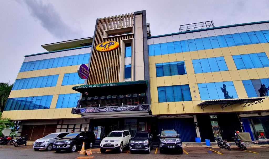 un gran edificio con coches estacionados frente a él en MP Hotel Kelapa Gading en Yakarta