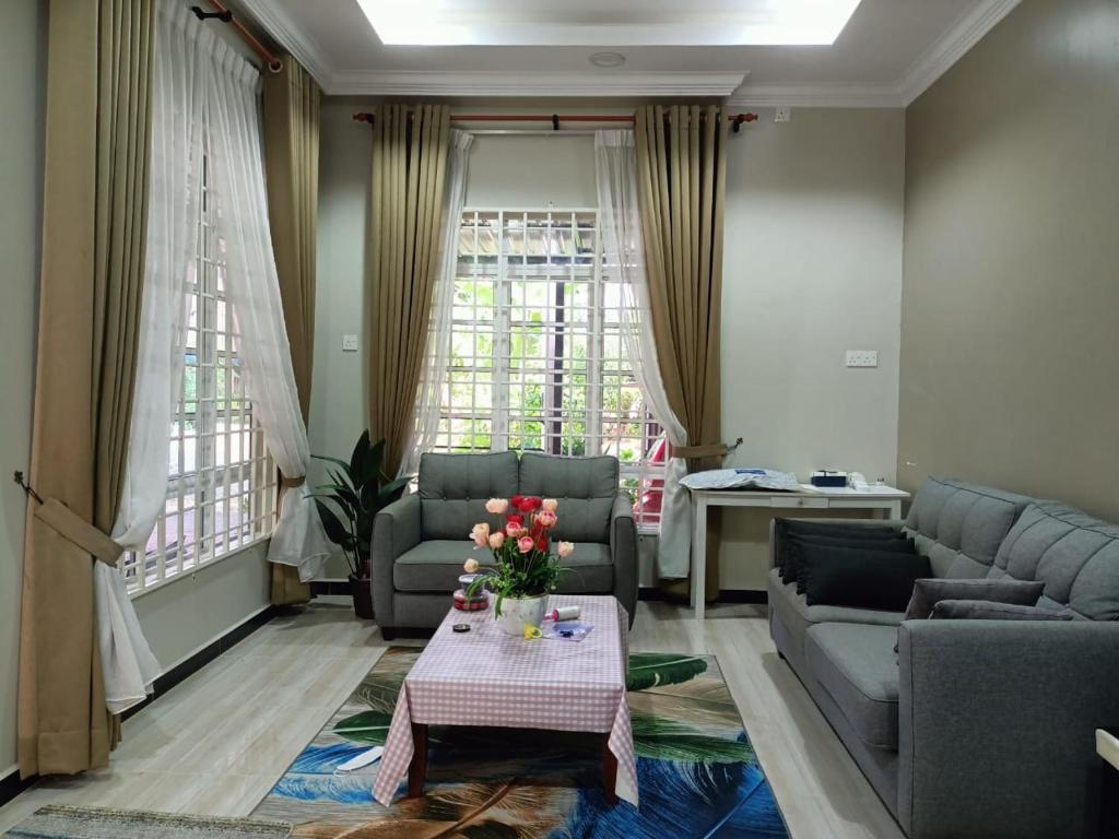 una sala de estar con sofás y una mesa con flores. en Sya Al-Yahya Homestay, en Kuala Terengganu