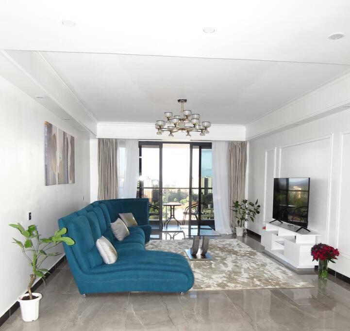a living room with a blue couch and a television at Three Bedroom Luxury Apartment in Nairobi
