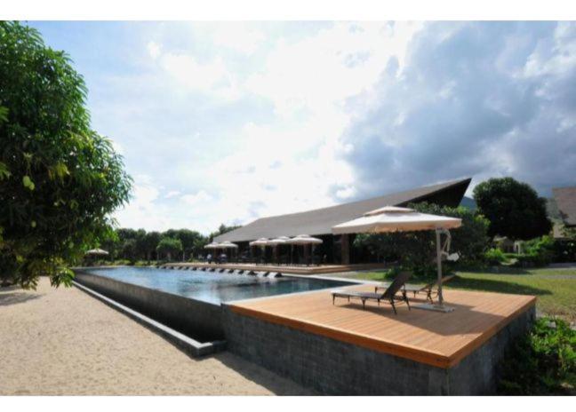 - une piscine avec un banc et un parasol à côté d'une rivière dans l'établissement Astoria Palawan, à San Jose