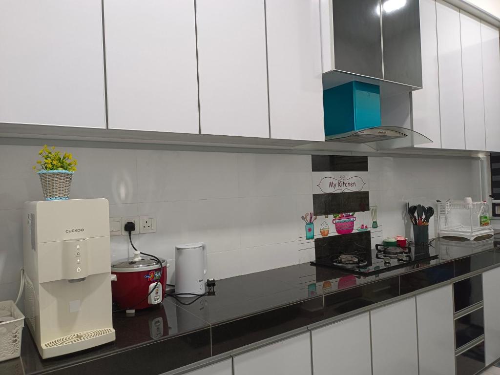 a kitchen with white cabinets and a counter top at TGG Homestay with Netflix in Kuala Terengganu