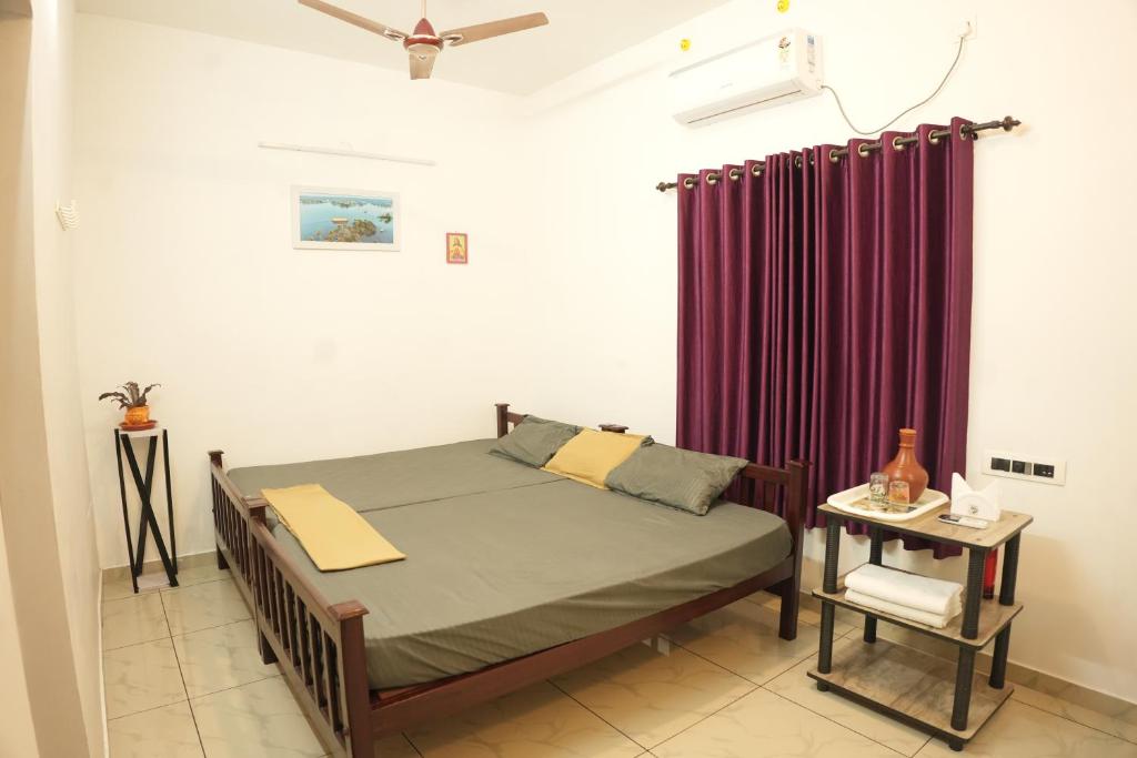 a bedroom with a bed and a purple curtain at Venitia Homestay in Alleppey