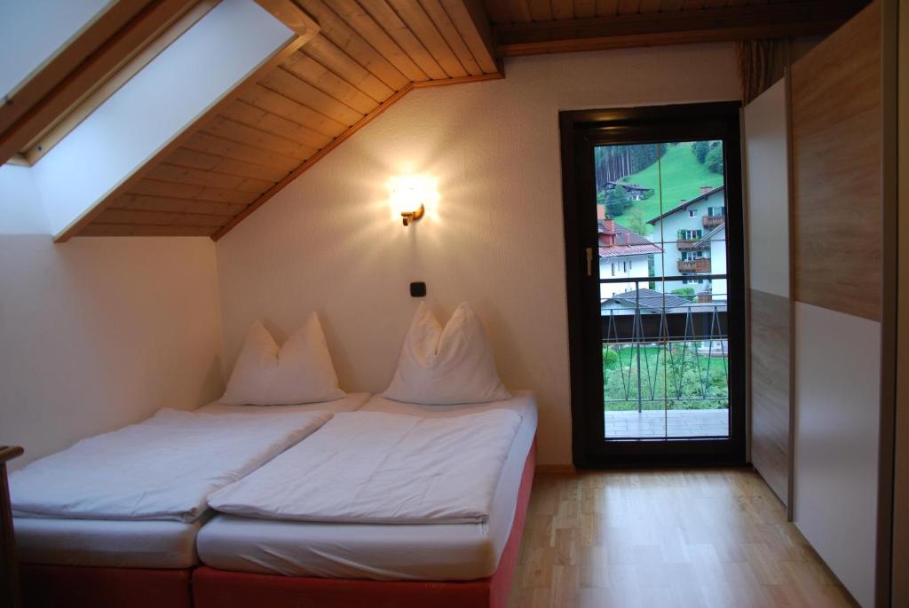 - une chambre avec un lit et une grande fenêtre dans l'établissement Apartmenthaus Maxl, à Bad Hofgastein