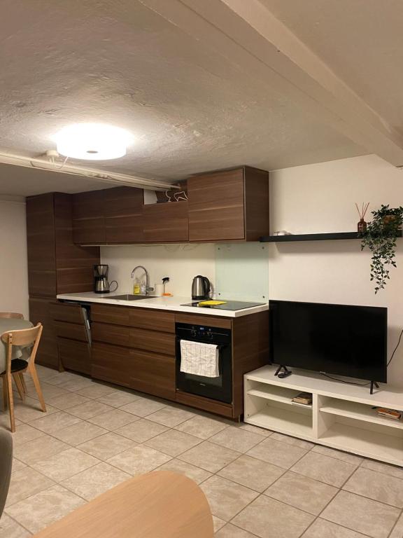 a kitchen with wooden cabinets and a flat screen tv at Nice apartment in Odense in Odense