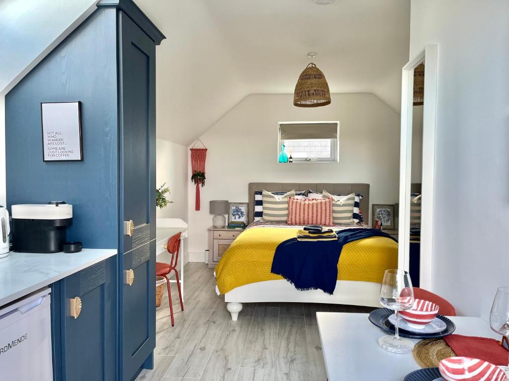 a bedroom with a yellow and blue bed and a kitchen at The Loft Curracloe, on Wexfords Coastal Scenic Route in Wexford