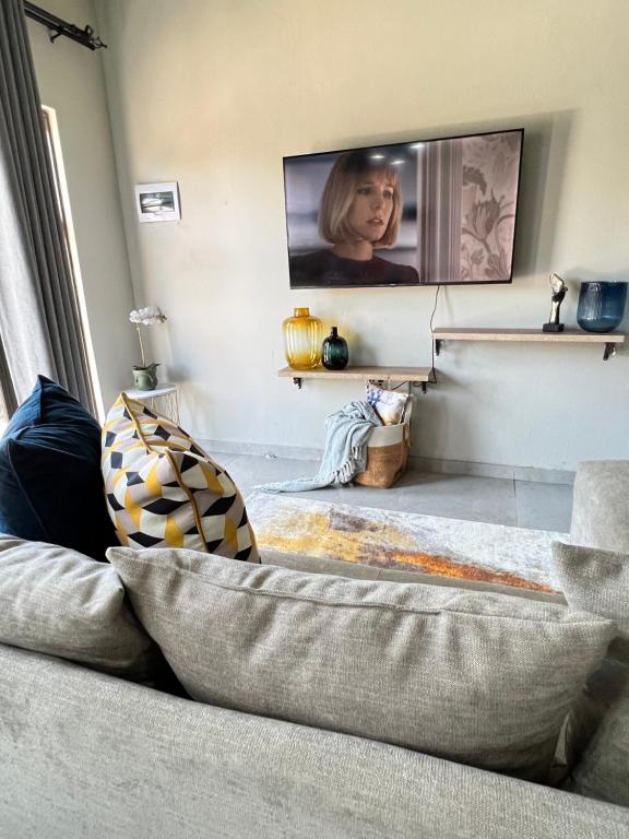 een woonkamer met een bank en een flatscreen-tv bij Serenity HideAway in Johannesburg