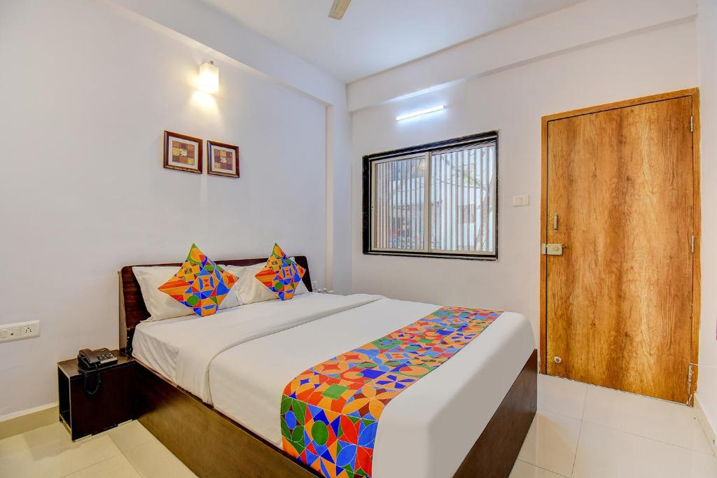 een slaapkamer met een bed en een houten deur bij FabExpress Sky Inn in Pune