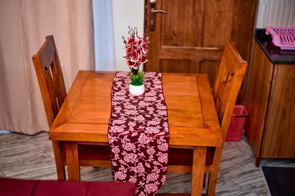 a wooden table with a table cloth with a vase of flowers on it at Kilimanjaro poa in Moshi