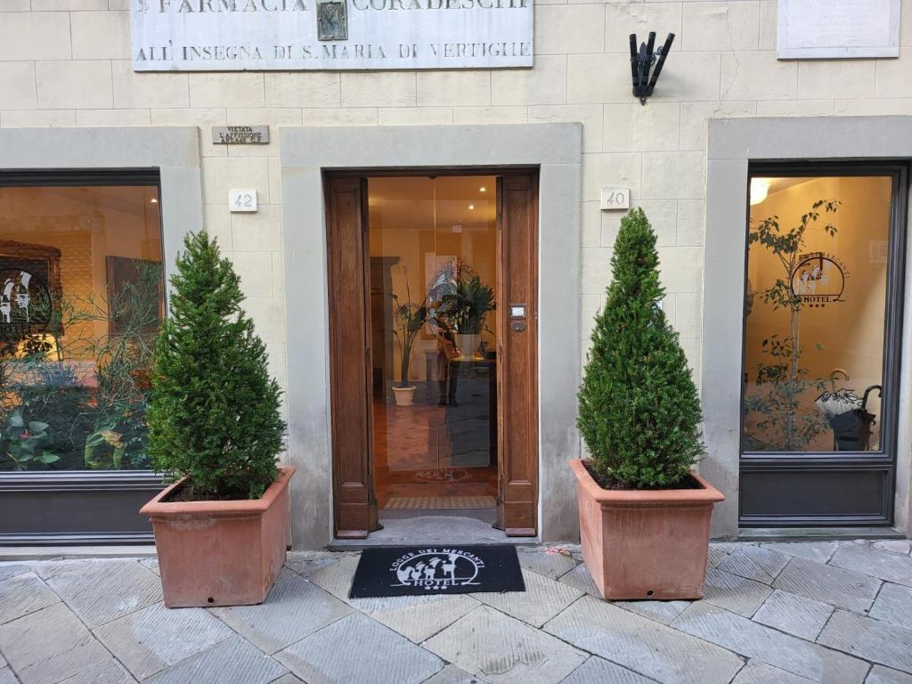 two potted trees in pots in front of a building at Hotel Logge Dei Mercanti in Monte San Savino