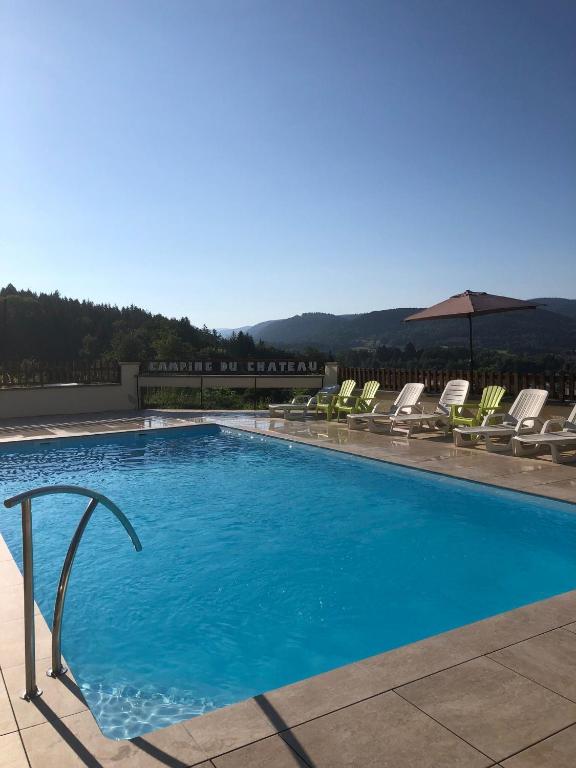 une grande piscine avec des chaises et un parasol dans l'établissement Camping du Château, à Granges-sur-Vologne