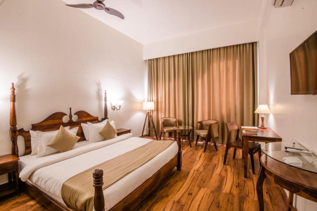 Habitación de hotel con cama y escritorio en New Royal Hotel, en Nueva Delhi