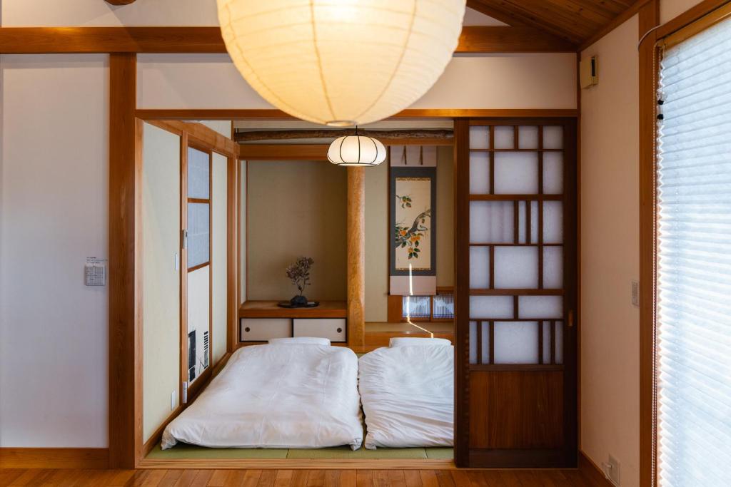 uma cama num quarto com um lustre em 合い宿 くまもと em Kumamoto