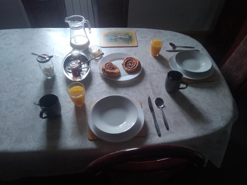 einen Tisch mit einem Teller mit Lebensmitteln und Gläsern Orangensaft in der Unterkunft Chambre d&#39;hôtes de puy faucher in Arrènes