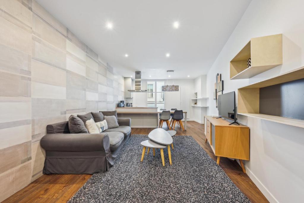 salon z kanapą i telewizorem w obiekcie Appartement charmant et lumineux en plein cœur de Paris w Paryżu