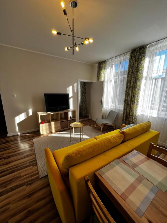 a living room with a yellow couch and a television at Lodging Młyńska Parking free in Bielsko-Biała