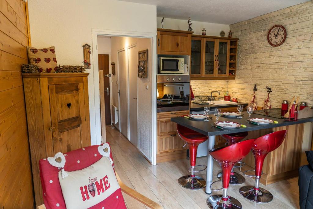 a kitchen with a counter and red stools in it at Résidence Les Ecrins - Studio pour 4 Personnes 224 in Les Orres