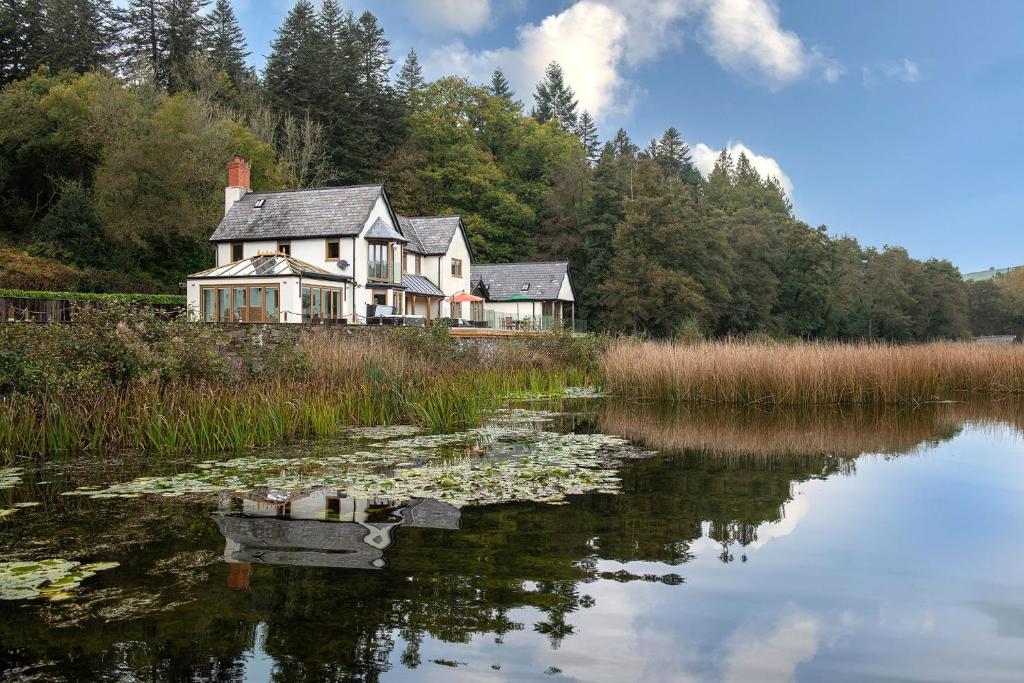 a house sitting on top of a lake with lily pads at Lake House in Brecon
