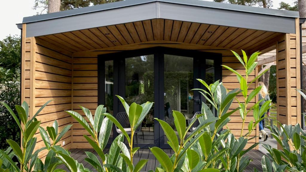 a wooden pergola with a glass door in a garden at SERENDIPITY - nature in luxury in Beekbergen