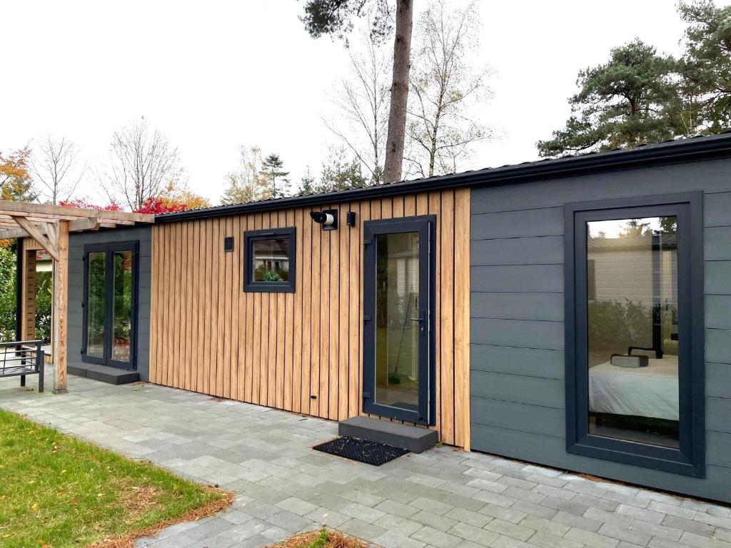 een klein huis met houten zijkanten op een patio bij Luxe Bos Cottage SERENDIPITY in Beekbergen