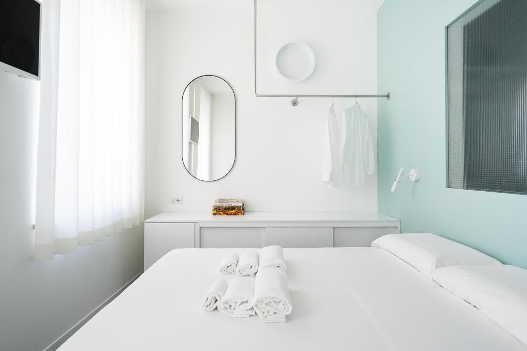 ein weißes Schlafzimmer mit einem weißen Bett und einem Spiegel in der Unterkunft VIVO in Civitanova Marche