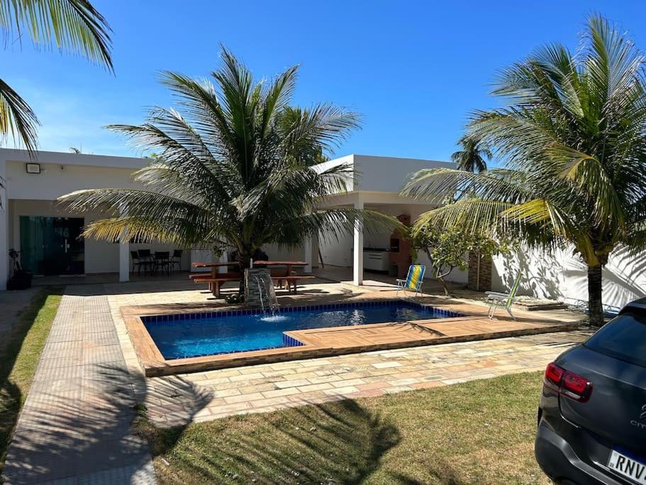 a swimming pool in front of a house with palm trees at Beachhouse in Barra do Sirinhaém in Barra do Sirinhaém